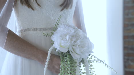 Bride-wearing-white-dress-at-wedding-holds-flower-bouquet