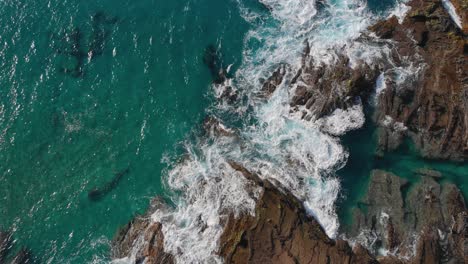 Top-down-view-of-the-waves-crashing-against-the-rocky-shore-at-Porto-das-Salemas