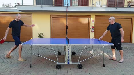 Couple-of-friends-play-ping-pong-outdoors-in-backyard