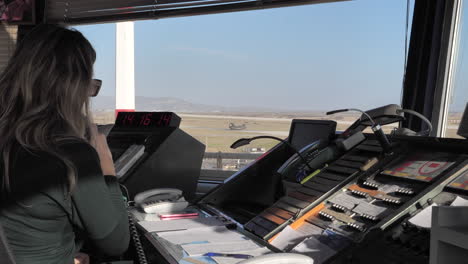 Medium-closeup-of-a-female-ATC-officer-talking-on-the-microphone-with-a-Chinook-helicopter-ready-for-take-off-on-the-runway