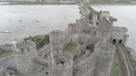 Medieval-landmark-historic-Conwy-castle-aerial-view-above-Welsh-seaside-landscape-rising-view