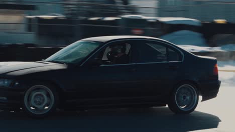 A-medium-shot-of-a-black-bmw-M3-drifting-past-the-camera