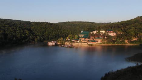 Niedrige-Luftaufnahme-Eines-Resorts-Am-Flussufer-In-Den-Hügeln-Der-Ukraine-Bei-Sonnenaufgang