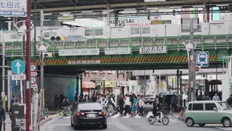 Gente-Cruzando-En-El-Carril-Peatonal-Bajo-La-Estación-Takadanobaba-En-Tokio,-Japón---Toma-Amplia