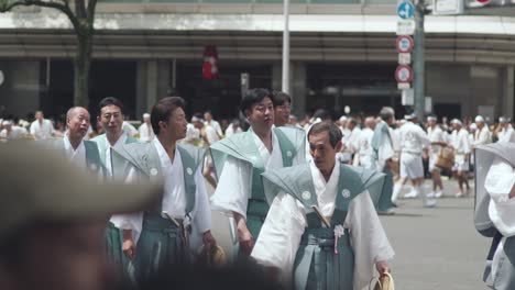 Hombres-Japoneses-Con-Trajes-Tradicionales-Caminando-En-La-Calle-Durante-Las-Procesiones-Yamaboko-Junko-Del-Desfile-De-Carrozas-Del-Festival-Gion-Matsuri-En-Kyoto,-Japón