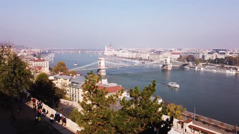 Statische-Aufnahme-Der-Budapester-Kettenbrücke-Aus-Großer-Entfernung-Mit-Booten-Auf-Der-Donau