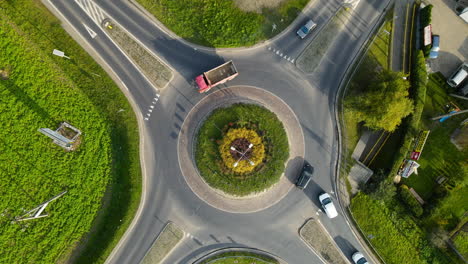 Top-View-Of-Vehicles-Passing-By-The-Roundabout-In-Lubawa,-Poland---orbiting-drone-shot,-slow-motion