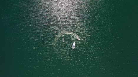 A-Speedboat-Moving-In-Circular-Motion-Towards-The-Stranded-Tour-Boat-In-The-Middle-Of-Turquoise-Ocean-In-Alaska---Aerial,-Drone-Shot