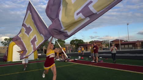 Cheerleader-Laufen-Mit-Fahnen-Vor-Einem-High-School-Footballspiel