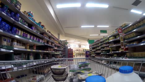 Inside-supermarket-shopping-cart-pushing-trolley-down-rice-aisle-as-customers-shop-during-corona-virus-pandemic