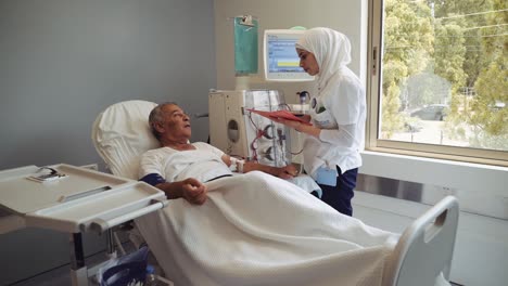 Muslim-Arab-Woman-Talking-To-A-Patient-Undergoing-Dialysis-Treatment---Medium-Shot