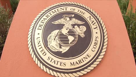 Camera-arc-down-to-bronze-emblem-of-the-Department-of-the-Navy-and-US-Marine-Corps,-Fountain-Park,-Fountain-Hills,-Arizona