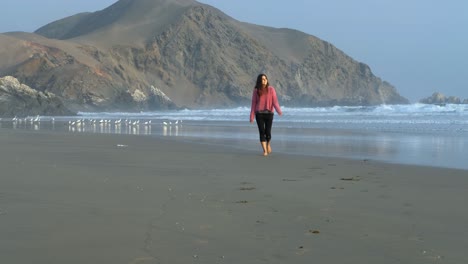 Hermosa-Chica-Feliz-Caminando-Hacia-La-Cámara-En-La-Playa,-En-Otoño