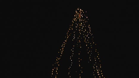Wide-tilt-up-shot-of-yellow-Fairy-String-Lights-hanging-on-Christmas-tree,-in-Rotterdam,-the-Netherlands