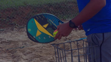 Man-gently-hitting-balls-over-the-net-for-Beach-Tennis-practice-in-Brasilia,-Brazil