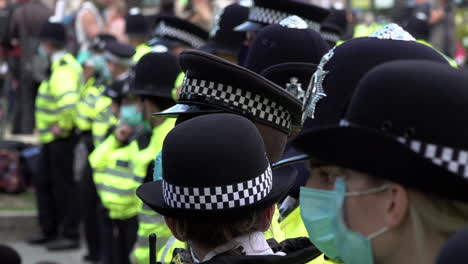 Polizisten-Der-Londoner-Metropolregion-Mit-Schutzmasken-Stehen-An-Einer-Absperrung-Schlange,-Während-Sie-Während-Der-Coronavirus-Pandemie-Einen-Protest-Gegen-Den-Klimawandel-überwachen