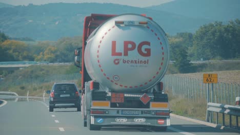 Truck-hauling-large-tank-with-fossil-fuel-driving-on-highway,-slow-motion
