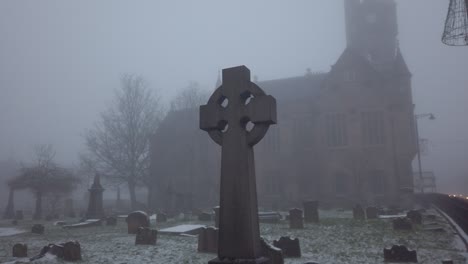 A-cross-gravestone-in-a-misty-graveyard