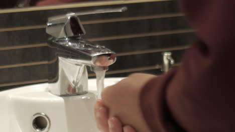 Close-up-shot-of-male-person-washing-hands-with-soap-in-sink-of-bathroom