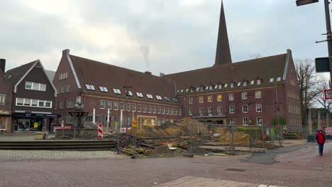 Wide-shot-of-construction-site-on-central-market-square-with-church-in-background-and-walking-people-in-the-city
