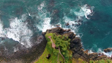 Top-down-aerial-view-on-viewpoint-on-oceanfront-cliff-washed-by-turquoise-ocean