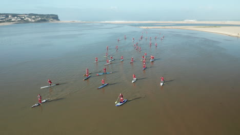 Panoramic-View-Of-Tranquil-Ocean-With-People-On-Paddle-Boards-Wearing-Santa-Claus-Clothes-In-Obidos-Lagoon,-Portugal