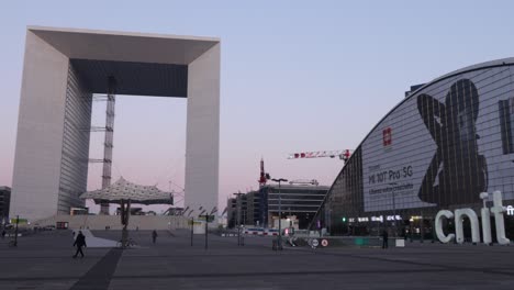 La-Defense-Plaza-during-early-morning-with-few-people,-the-Great-Arch-and-the-CNIT