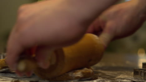 Slow-motion-close-up-view-of-hands-pushing-wooden-rolling-pin-over-gingerbread-dough