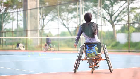 Yogyakarta,-Indonesia---May-2,-2021-:-Veiled-asian-woman-in-wheelchair-playing-tennis-on-court