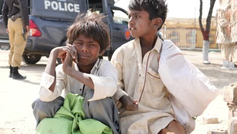 Zwei-Kleine-Arme-Kinder-Sitzen-Draußen-Auf-Der-Straße-In-Tharparkar,-Pakistan
