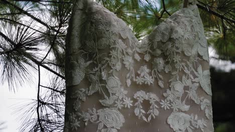 Wunderschöne-Nahaufnahme-Eines-Designer-Hochzeitskleides,-Das-An-Einem-Baum-Im-Garten-Hängt,-In-Zeitlupe