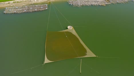 Drone-view-of-a-fisherman-is-preparing-fishing-trap-on-the-river-for-catching-fish