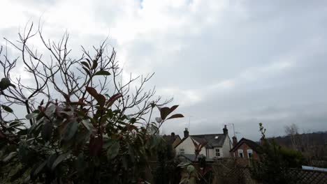 Pan-left-to-right-time-lapse-of-two-way-moving-gray-clouds-in-the-back-garden