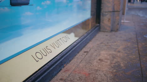 Close-view-of-Louis-Vuitton-logo-by-display-window-on-street,-slomo