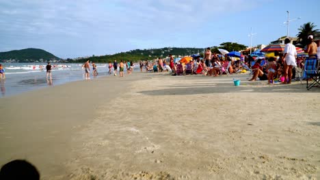 Dolly-in-of-kids-playing-in-the-sand-and-families-resting-by-the-shore-in-Bombas-and-Bombinhas-beaches-Brazil