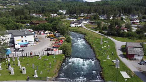 Storelva-river-in-Byrkjelo-town-center---Upstream-aerial-passing-controversial-kleppeparken-sculpture-park-and-industrial-scrapyard-area---Norway