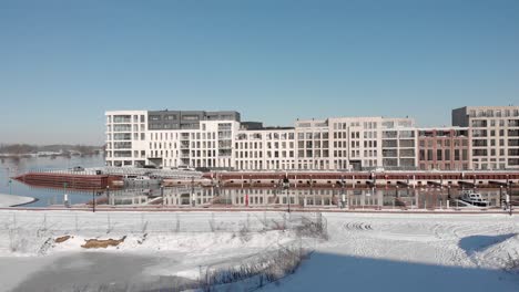 Noorderhaven-aerial-approach-of-contemporary-new-luxury-apartment-building-in-bright-snow-cityscape-mirrored-in-the-high-water-level-in-the-recreational-port-in-the-foreground