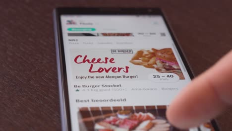Person-using-smartphone,-browsing-through-restaurant-pictures-on-Deliveroo-app