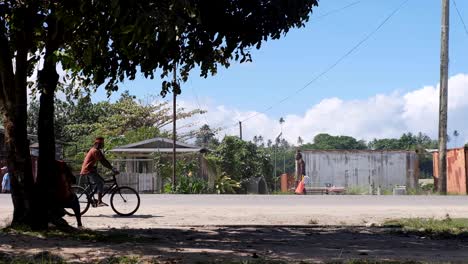 Un-Hombre-Que-Monta-Una-Bicicleta-Y-El-Tráfico-Diario-En-La-Ciudad-De-Buka-En-La-Región-Autónoma-De-La-Isla-Tropical-De-Bougainville,-Papua-Nueva-Guinea