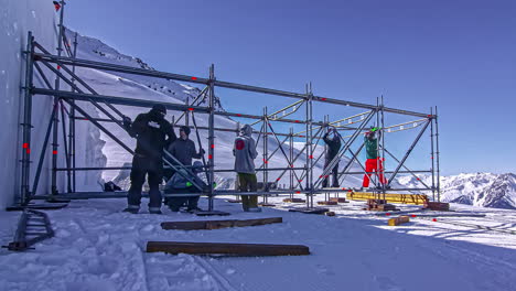 Grupo-De-Trabajadores-Construyen-Andamios-De-Construcción-Con-Escaleras-Para-Puestos-En-Montañas-Nevadas-Durante-El-Día-Soleado-En-Montafon,-Austria