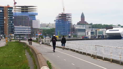 Rückansicht-Einer-Frau,-Die-Auf-Einem-Elektroroller-An-Der-Promenade-Am-Fluss-Gota-In-Göteborg,-Schweden,-Fährt