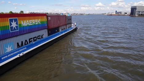 Gira-Mundial-De-Contenedores-Arcoíris-De-Maersk-En-La-Barcaza-De-Carga-Mercurius-Navegando-En-El-Río-Noord-En-Kinderdijk,-Países-Bajos