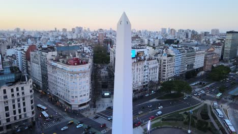 Drone-Sobrevuela-El-Icónico-Monumento-Obelisco-De-Buenos-Aires-Adecuado-En-Republic-Square-En-La-Intersección-De-Las-Avenidas-Running-Y-9th-Of-July-Con-El-Paisaje-Urbano-Del-Centro-En-El-Fondo