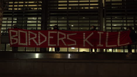 Demonstranten-Halten-Nachts-Vor-Dem-Britischen-Innenministerium-Ein-Großes-Rotes-Banner-Mit-Der-Aufschrift-„Grenzen-Töten“-Hoch,-Um-Für-Die-Rechte-Von-Flüchtlingen-Zu-Protestieren