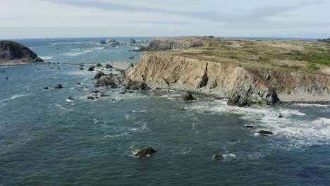 Stationary-drone-aerial-of-tall-sea-cliffs-at-the-Pacific-ocean