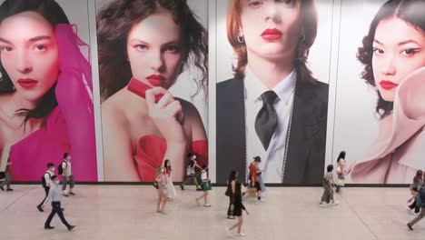 Grandes-Multitudes-De-Viajeros-Pasan-Frente-A-Un-Gran-Anuncio-Comercial-En-La-Estación-De-Metro-De-Hong-Kong-Mtr-Temprano-En-La-Mañana-En-El-Distrito-Central,-Hong-Kong