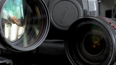 Ein-Paar-Canon-Teleobjektive-Auf-Dem-Schreibtisch-Mit-Dem-Gehäuse-Einer-DSLR-Kamera-Im-Hintergrund