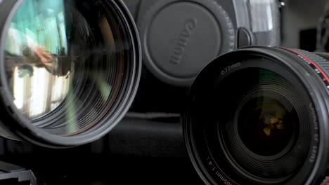 Pair-Of-Canon-Telephoto-Lens-On-Desk-With-Body-Of-DSLR-Camera-Body-In-Background