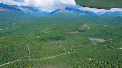 Small-airplane-flight-over-the-Matanuska-River-with-the-mountains-of-the-Talkeetna-Range-in-the-distance-west-of-Palmer,-Alaska