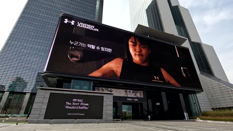 Giant-electronic-billboard-advertising-products-outside-the-Coex-Artium-World-Trade-Center-complex-in-Seoul,-South-Korea---establishing-shot